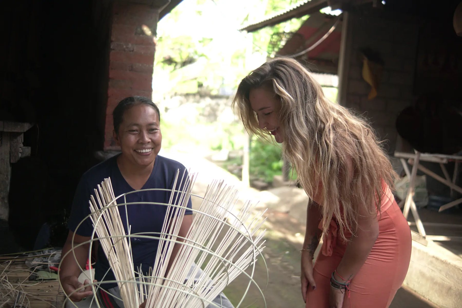 Marije and a craftswoman laughing while weaving bamboo