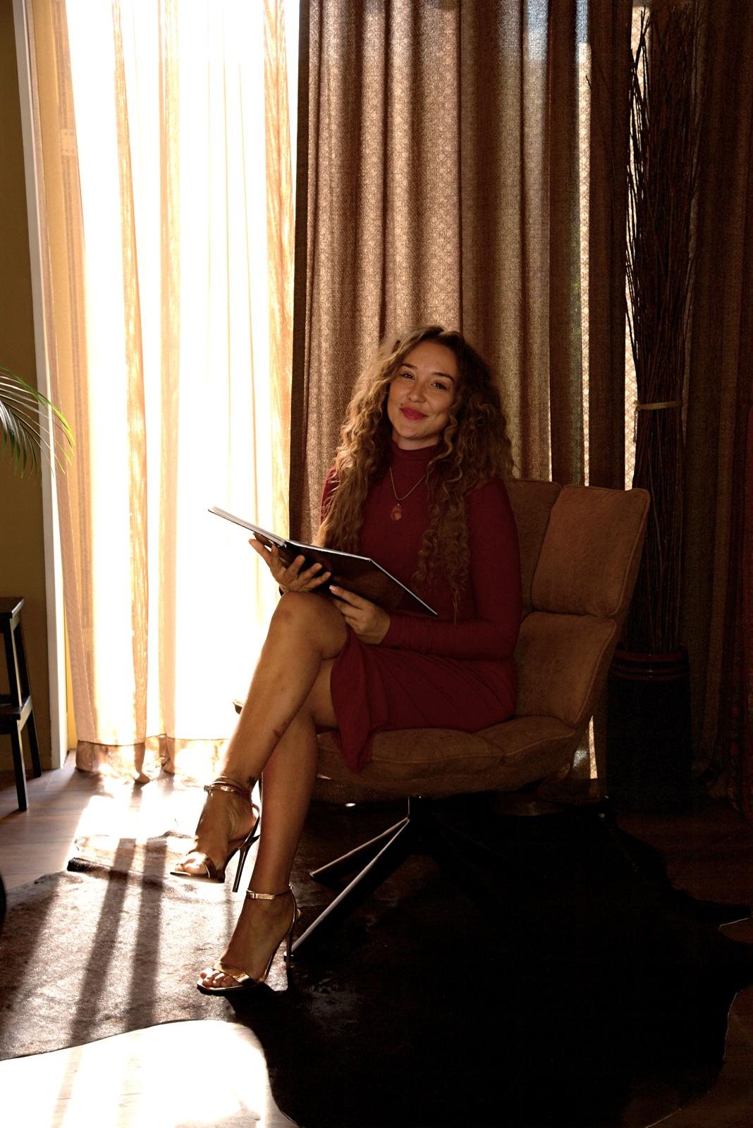 Marije Andrea seated in a leather armchair holding a portfolio