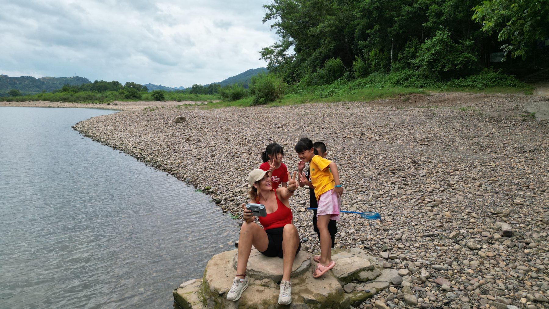 Marije sitting with local children on a rock by the water